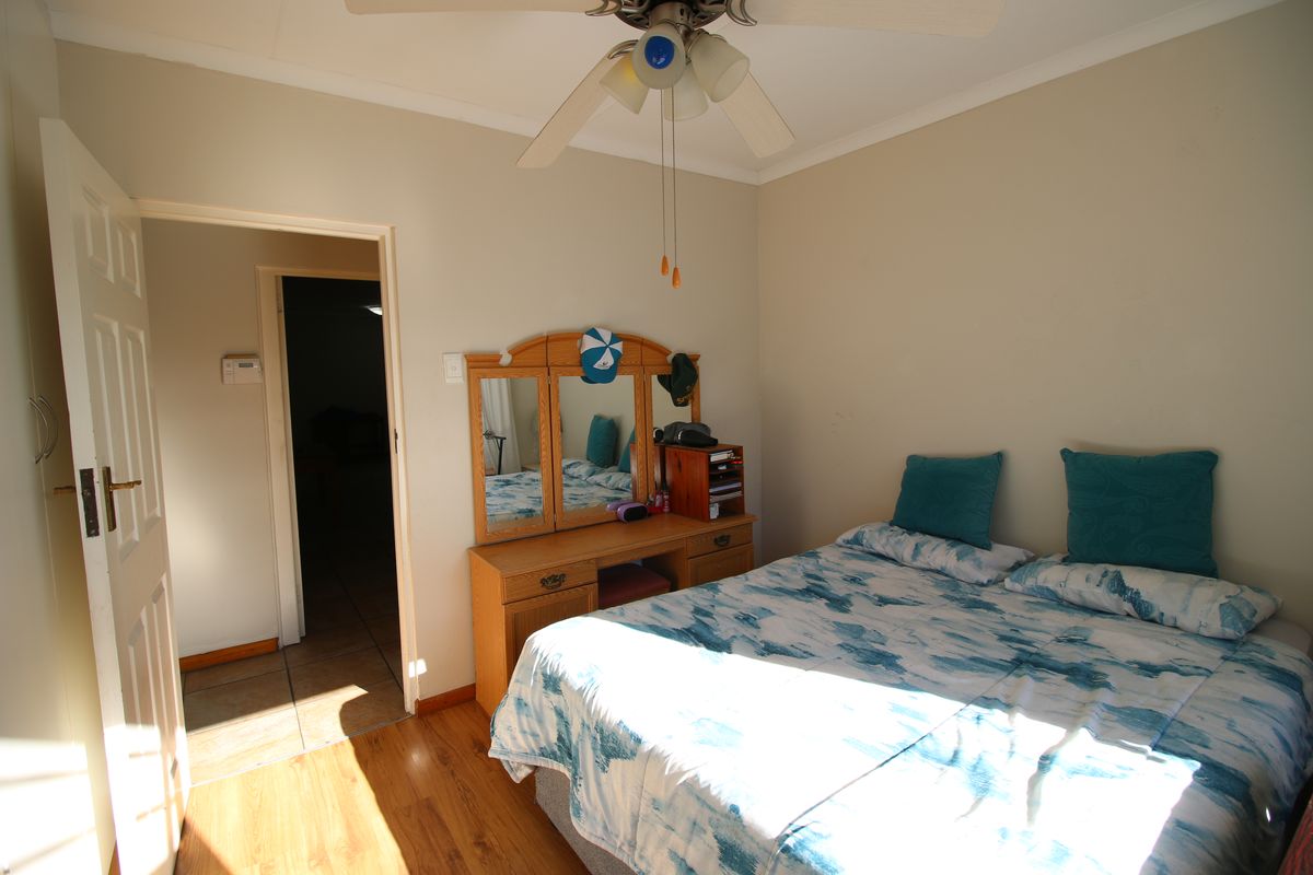 A functional bedroom featuring laminate flooring, a ceiling fan, and neutral wall finishes, providing a comfortable and well-lit sleeping space.