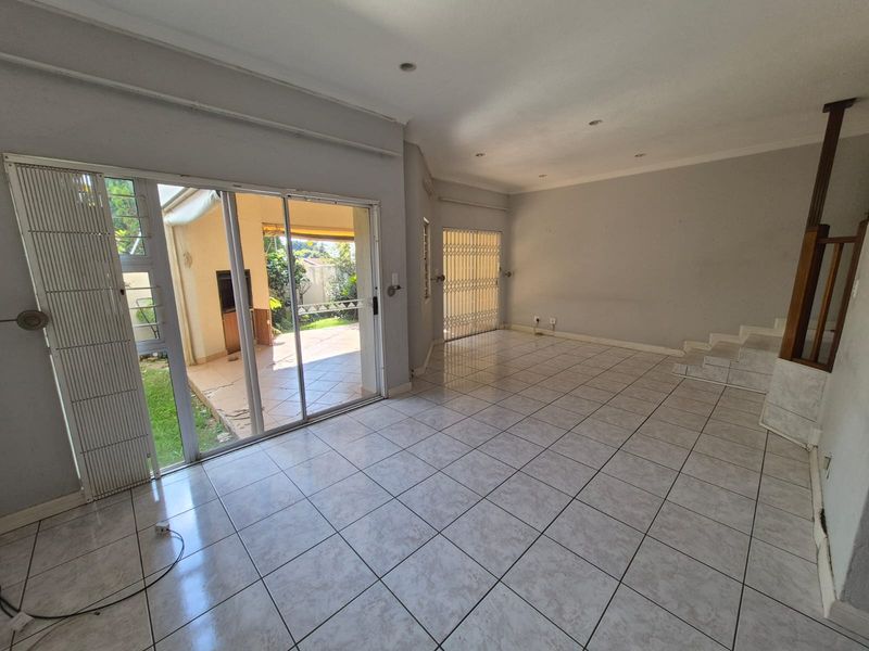 Spacious, empty living area featuring tiled flooring, recessed lighting, and large sliding glass doors providing direct access to the outdoor patio area.