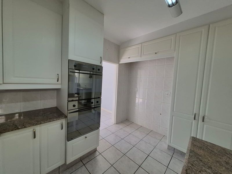 A functional kitchen featuring built-in cabinetry, granite countertops, a double oven, and tiled finishes throughout.