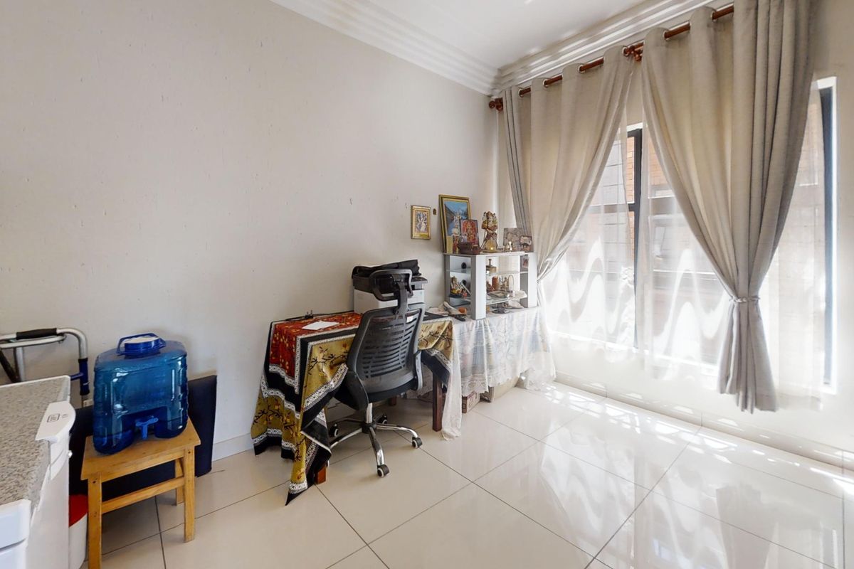 A bright living area featuring polished tiled flooring, coved ceiling cornices, and large windows dressed with curtains.