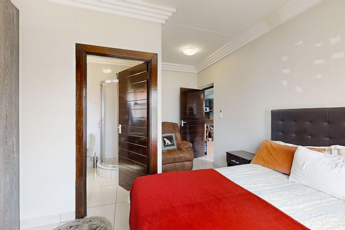 A bedroom featuring tiled flooring, crown molding, and an en-suite bathroom with a shower enclosure.