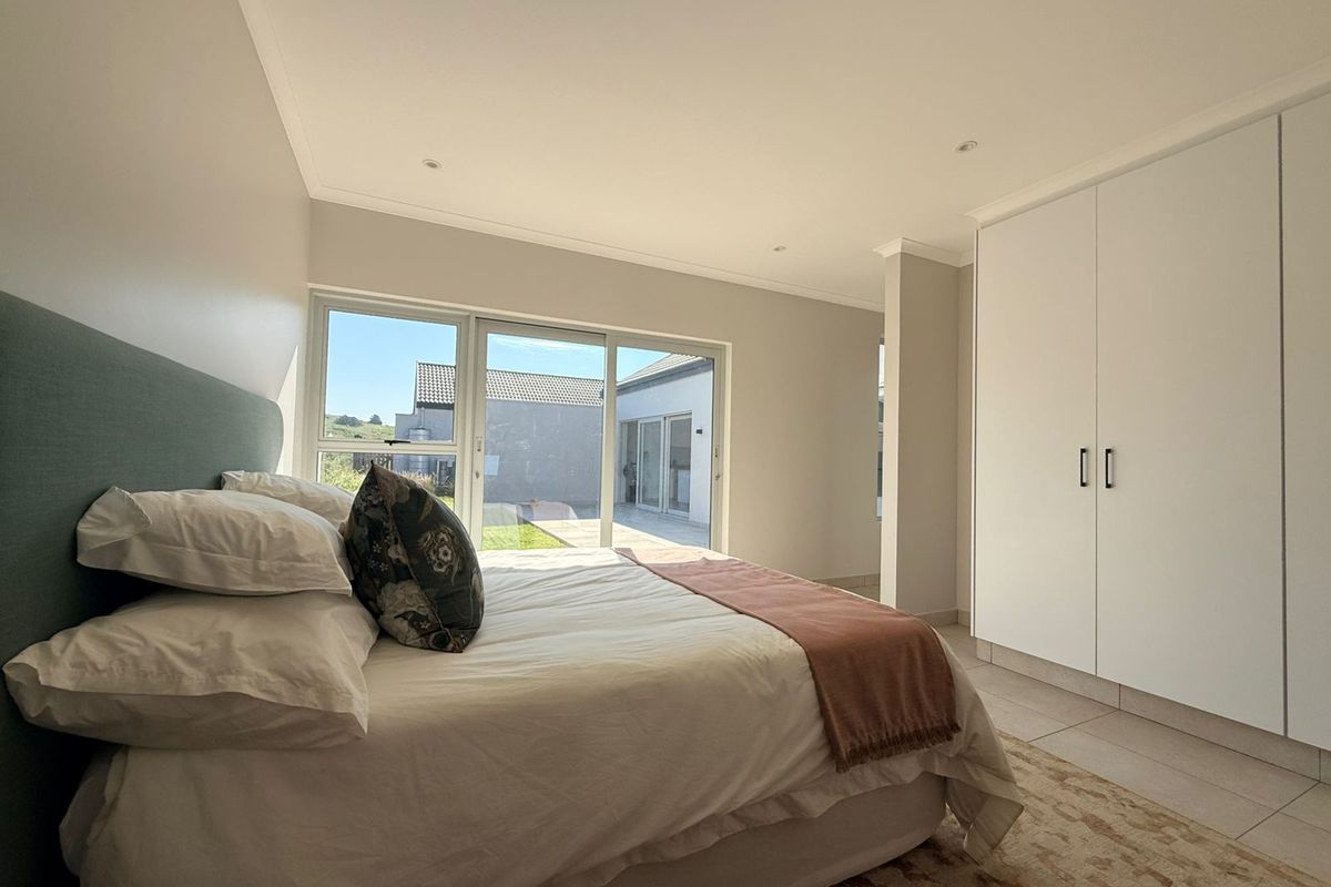 A bright bedroom featuring built-in cupboards, tiled flooring, and large sliding glass doors that provide access to the outdoor area.