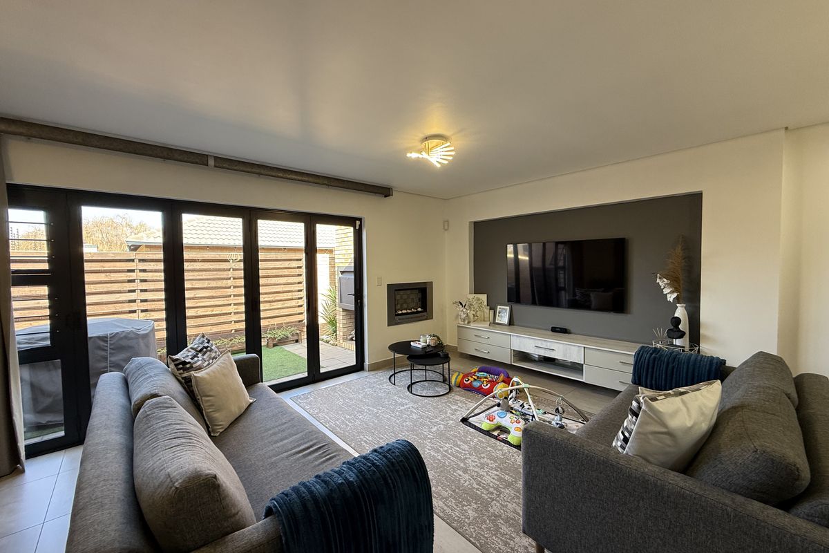 Modern living room featuring a built-in fireplace, custom media cabinetry, and large bi-fold doors providing seamless access to the outdoor patio area.