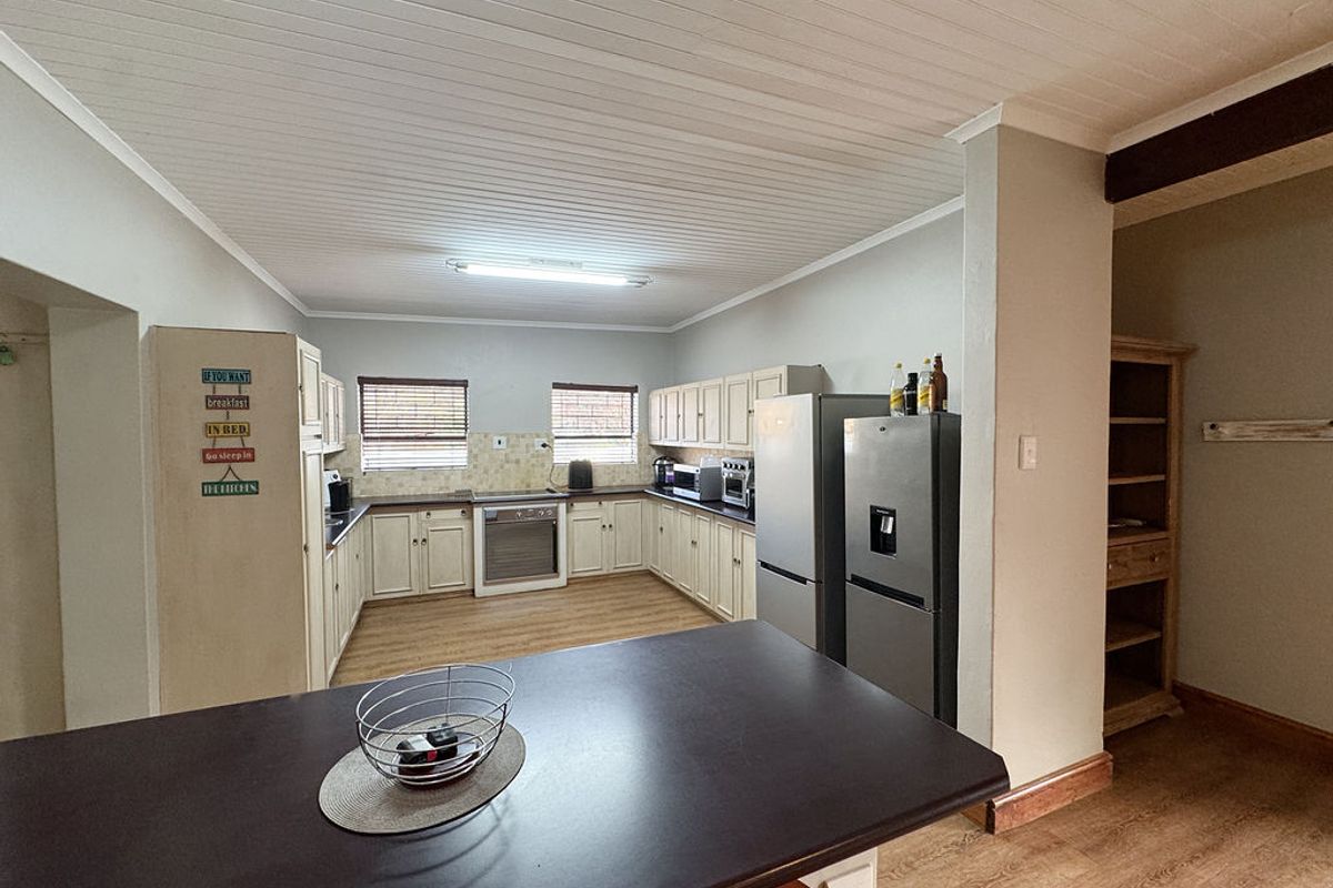 Spacious kitchen featuring U-shaped cabinetry, built-in oven, hob, and a central breakfast counter, offering functional workspace and ample storage.