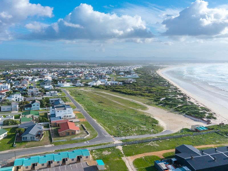 An elevated aerial view showcasing the coastal residential estate, surrounding landscape, and proximity to the beach.