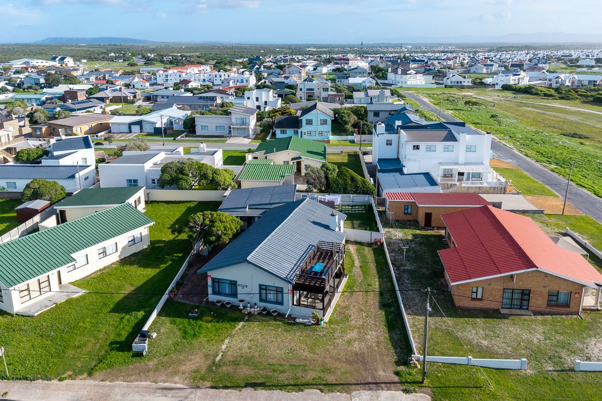 Aerial view of the property showing the house, metal roof, timber deck, and surrounding residential neighborhood.