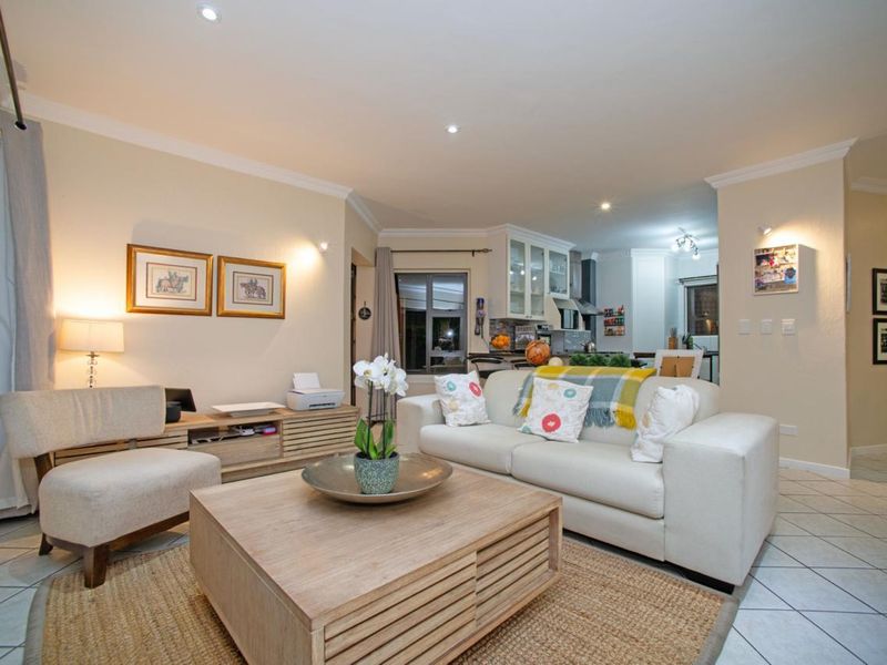 An open-plan living area featuring tiled flooring, recessed downlighting, and a seamless transition into the adjacent kitchen space.