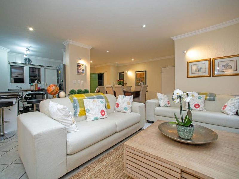 Spacious open-plan living area featuring a modern kitchen with breakfast bar, dining space, and comfortable lounge area with recessed downlighting.