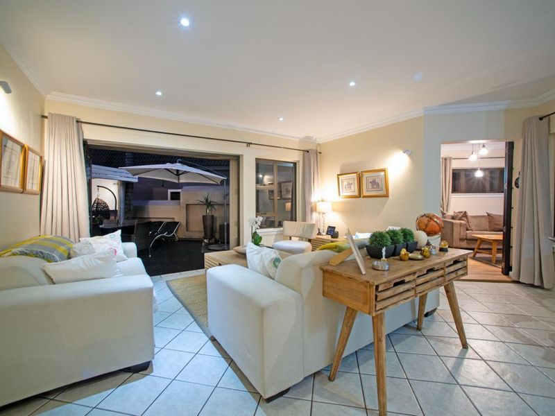 Spacious open-plan living area featuring tiled flooring, recessed downlighting, and large sliding doors providing seamless access to the outdoor patio.