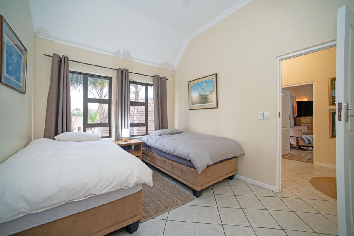 A bedroom featuring high vaulted ceilings, tiled flooring, and large windows that provide natural light and views of the surrounding area.
