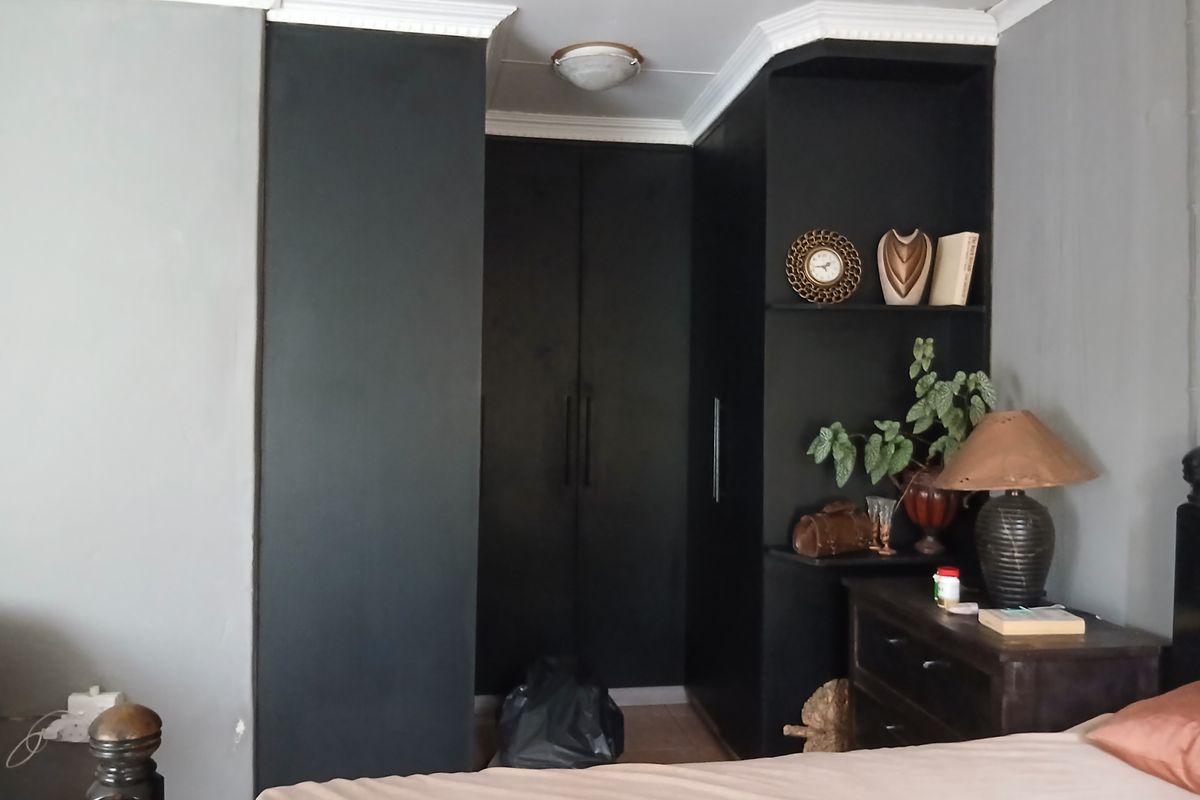 Bedroom featuring built-in black cabinetry with integrated shelving and decorative crown molding.