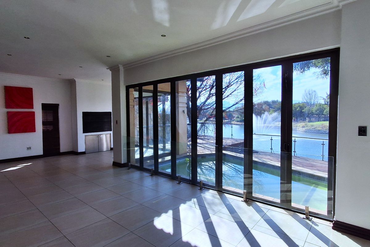 Spacious open-plan living area featuring large stacking glass doors that open onto a pool deck with scenic lake views.