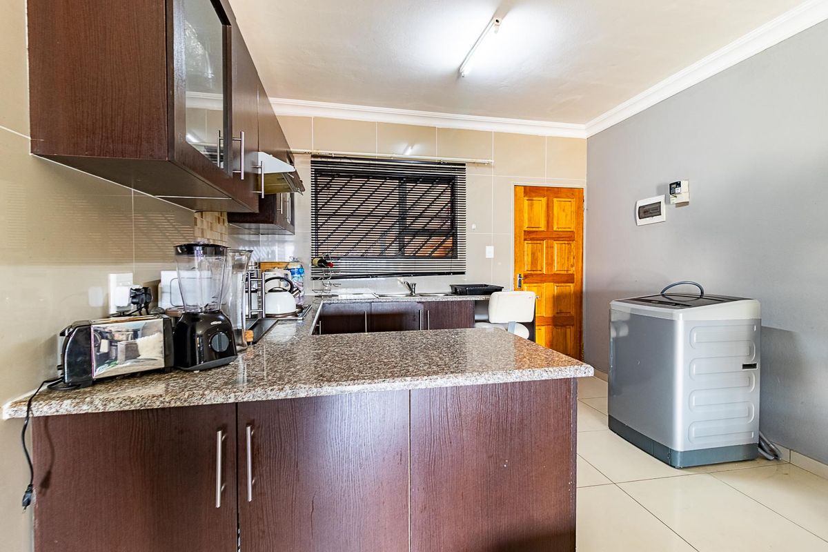 Functional kitchen featuring dark wood cabinetry, granite countertops, tiled backsplash, and neutral floor tiles, offering a practical layout for daily meal preparation.