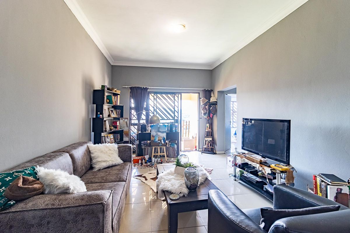 A well-lit living room featuring tiled flooring, neutral wall tones, and a sliding glass door providing access to an outdoor area.