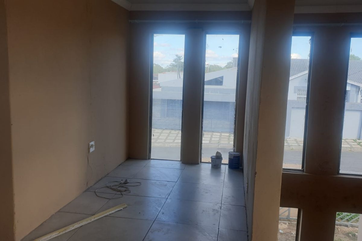 An empty, unfinished room featuring large windows with views of the street and surrounding neighborhood, offering a blank canvas for renovation.