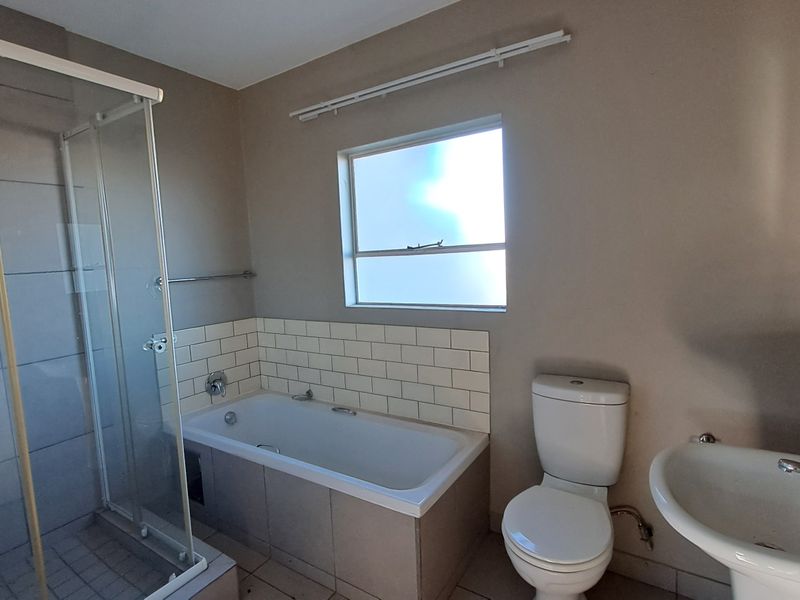 A functional bathroom featuring a separate shower enclosure, bathtub with subway tile splashback, pedestal basin, and toilet, finished with neutral wall tones.