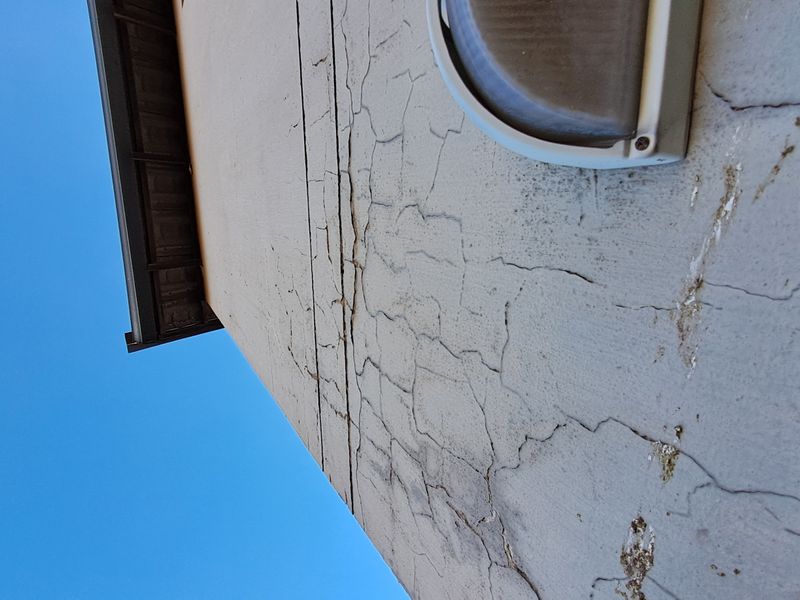 Close-up view of an exterior wall showing significant surface cracking and deterioration of the wall finish.