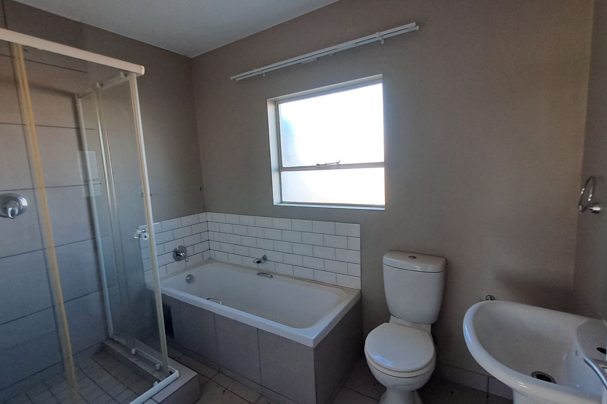 A functional bathroom featuring a shower enclosure, bathtub with subway tile splashback, pedestal basin, and toilet.