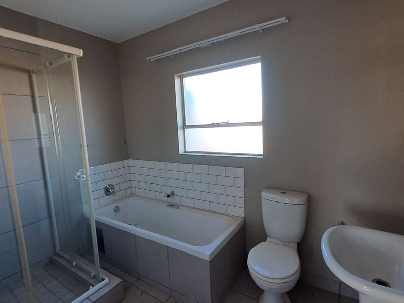A functional bathroom featuring a shower enclosure, bathtub with subway tile splashback, pedestal basin, and toilet.
