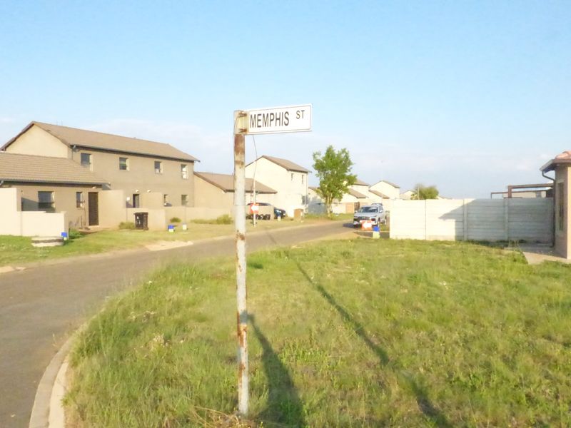 A street view showing the residential neighbourhood approach with paved roads and surrounding townhouse properties.