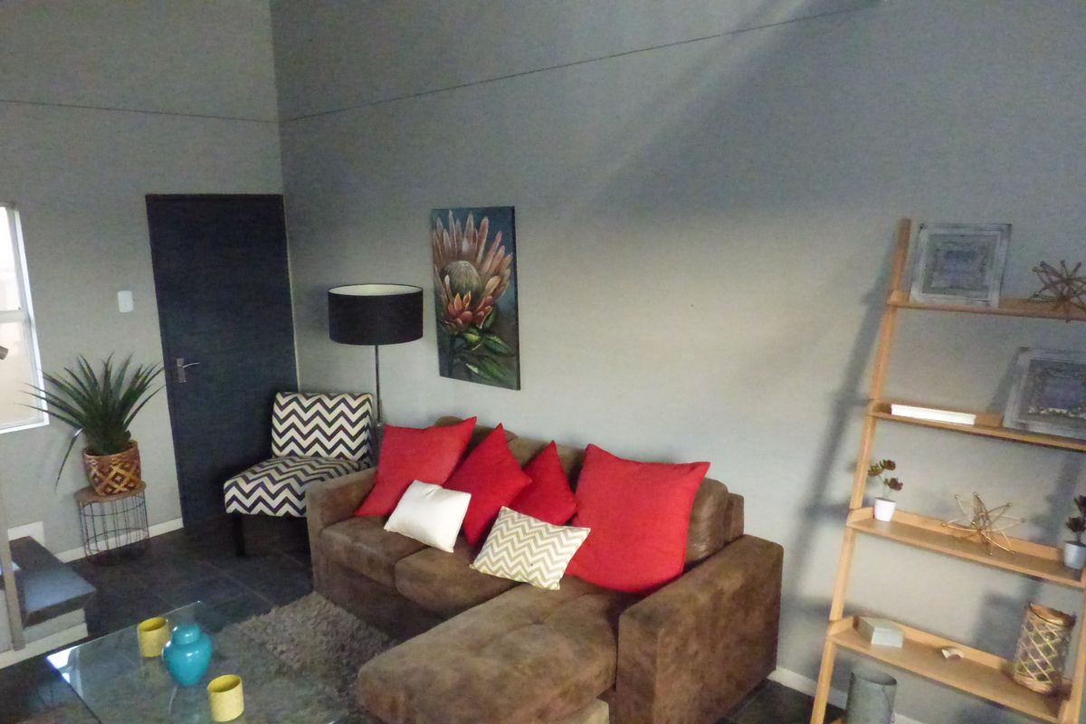 A living room area featuring tiled flooring and an adjacent staircase with a metal handrail.