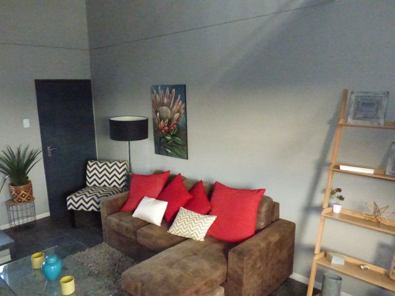 A living room area featuring tiled flooring and an adjacent staircase with a metal handrail.