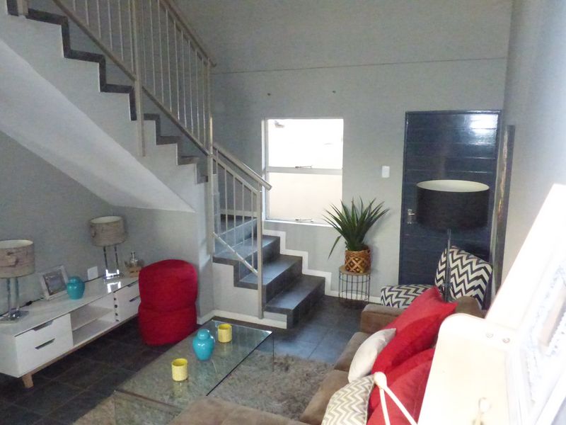 Open plan living area featuring a staircase with metal balustrade, tiled flooring, and direct access to adjacent rooms.