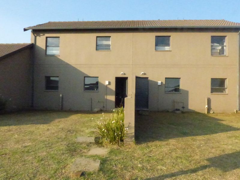 Front elevation of a two-story townhouse featuring a plastered facade, tiled roof, and small front garden area.