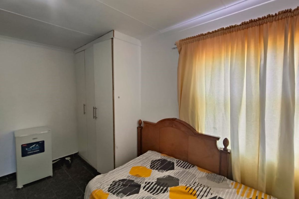 A functional bedroom featuring a built-in wardrobe and tiled flooring, offering a neutral space ready for personalization.
