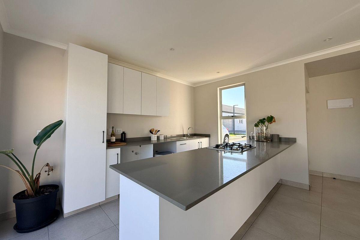 Modern kitchen featuring white cabinetry, stone countertops, a gas hob, and tiled flooring, offering a clean and functional workspace.