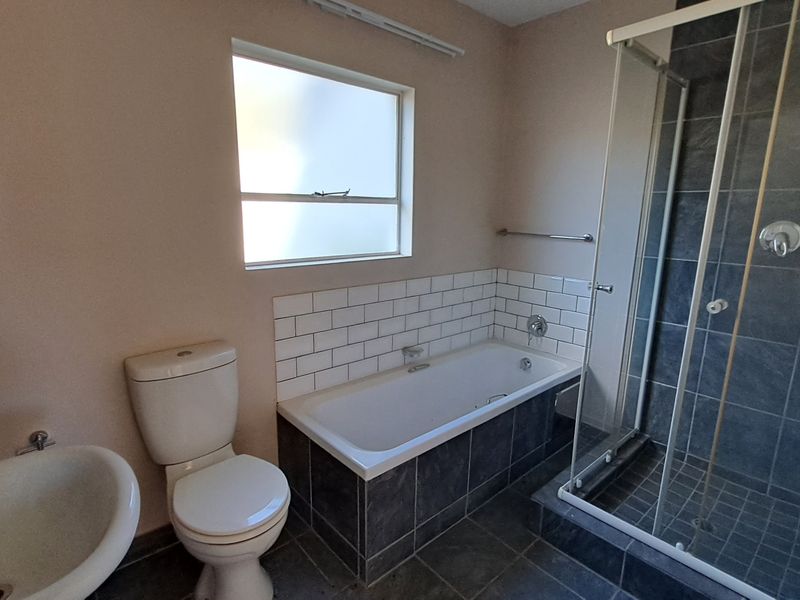 A clean, functional bathroom featuring a separate glass-enclosed shower, a built-in bathtub with subway tile surround, a pedestal basin, and a toilet.