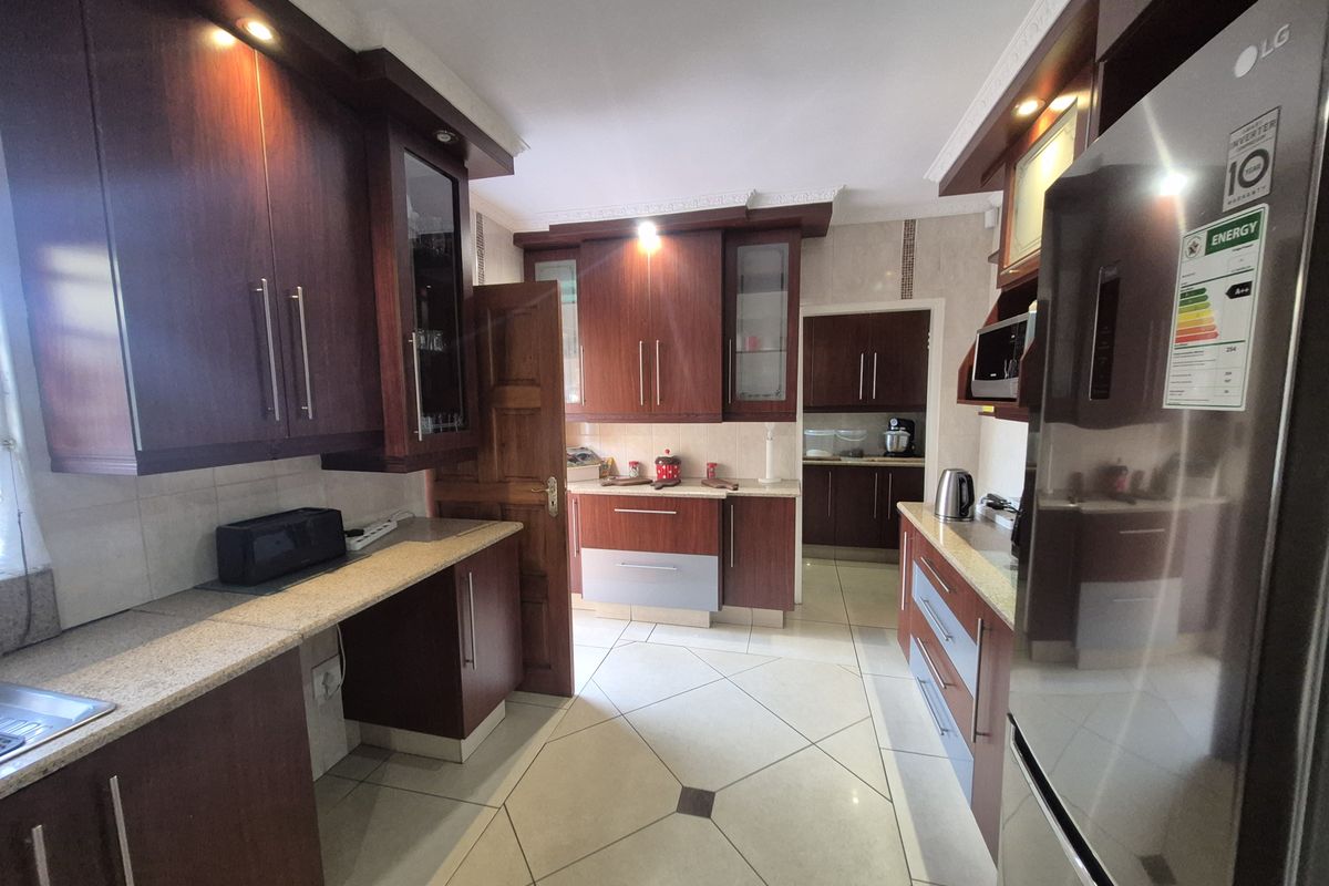 A well-maintained kitchen featuring dark wood cabinetry, granite countertops, tiled flooring, and integrated lighting, offering a functional and classic workspace.