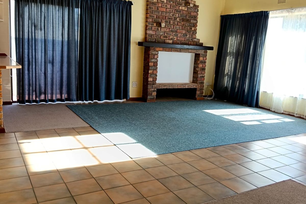 Spacious living room featuring a prominent brick fireplace, tiled flooring, and large sliding glass doors providing access to the exterior.