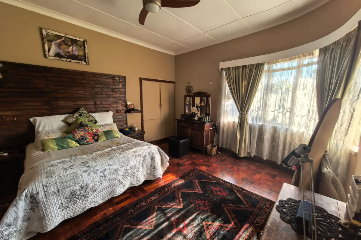 Spacious bedroom featuring warm parquet flooring, a ceiling fan, and large windows that provide ample natural light.