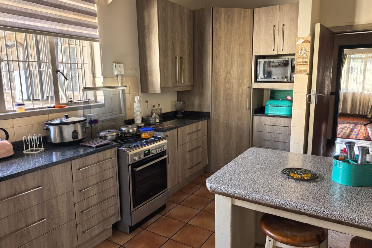 Functional kitchen featuring wood-look cabinetry, granite countertops, a freestanding gas stove, and a central island with breakfast seating.