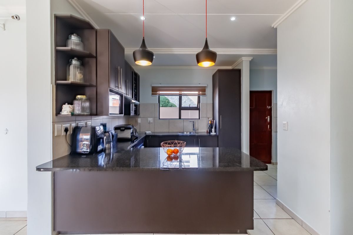 Modern kitchen featuring dark cabinetry, granite countertops, a breakfast bar, and integrated lighting, creating a functional and stylish culinary space.
