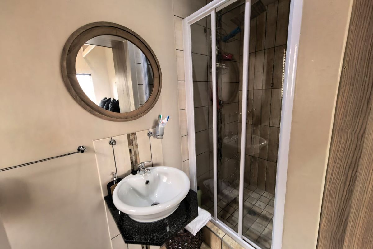 Compact bathroom featuring a vessel sink on a granite vanity top and a glass-enclosed shower with tiled walls.