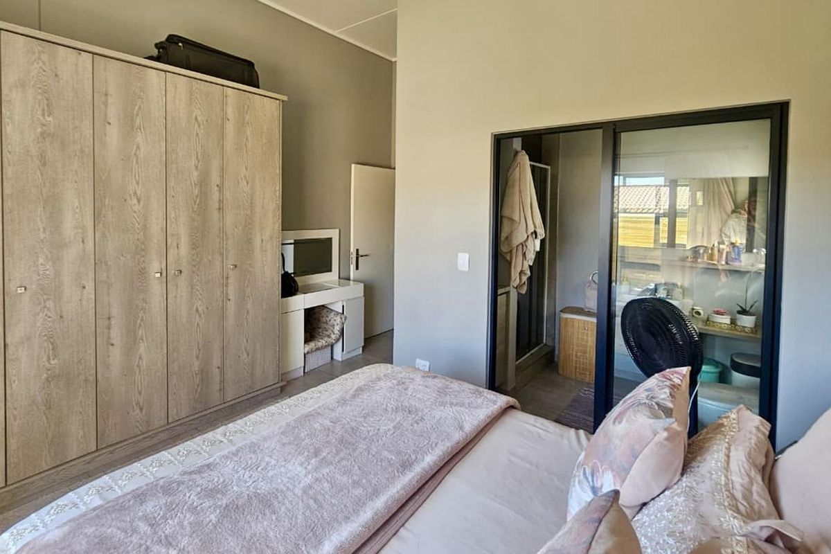 A well-maintained bedroom featuring a large built-in wardrobe and a sliding glass door providing access to an en-suite bathroom.