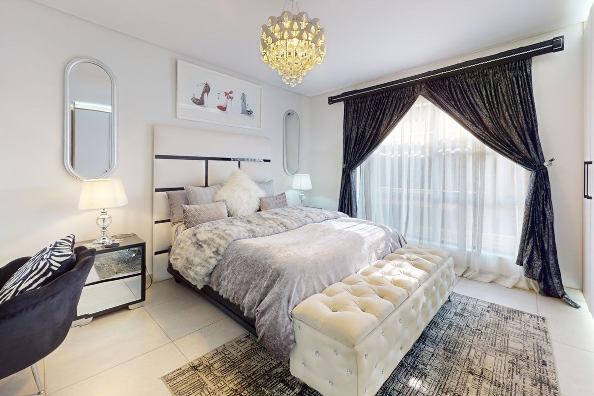 A well-maintained bedroom featuring tiled flooring, a built-in wardrobe, and an elegant crystal chandelier, offering a bright and comfortable living space.