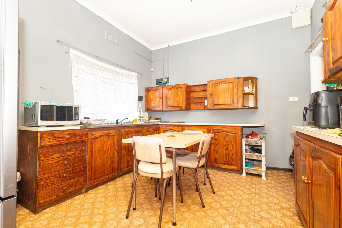 A dated kitchen featuring traditional wooden cabinetry, vinyl flooring, and a functional layout with ample storage space.