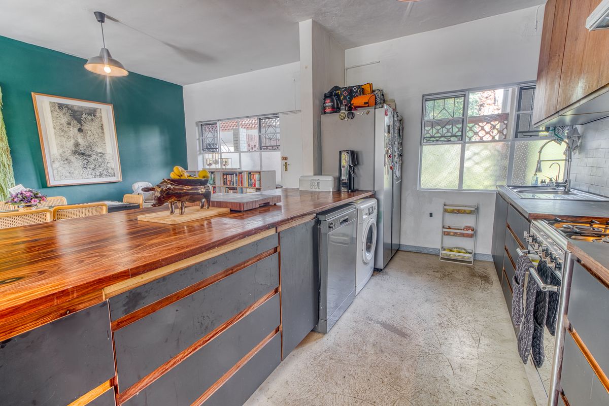 A functional kitchen featuring a large wooden island, gas stove, and built-in cabinetry, with an open-plan layout connecting to the living area.