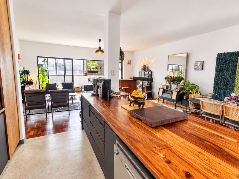Spacious open-plan living area featuring a large wooden kitchen island, parquet flooring, and expansive sliding glass doors leading to an outdoor space.