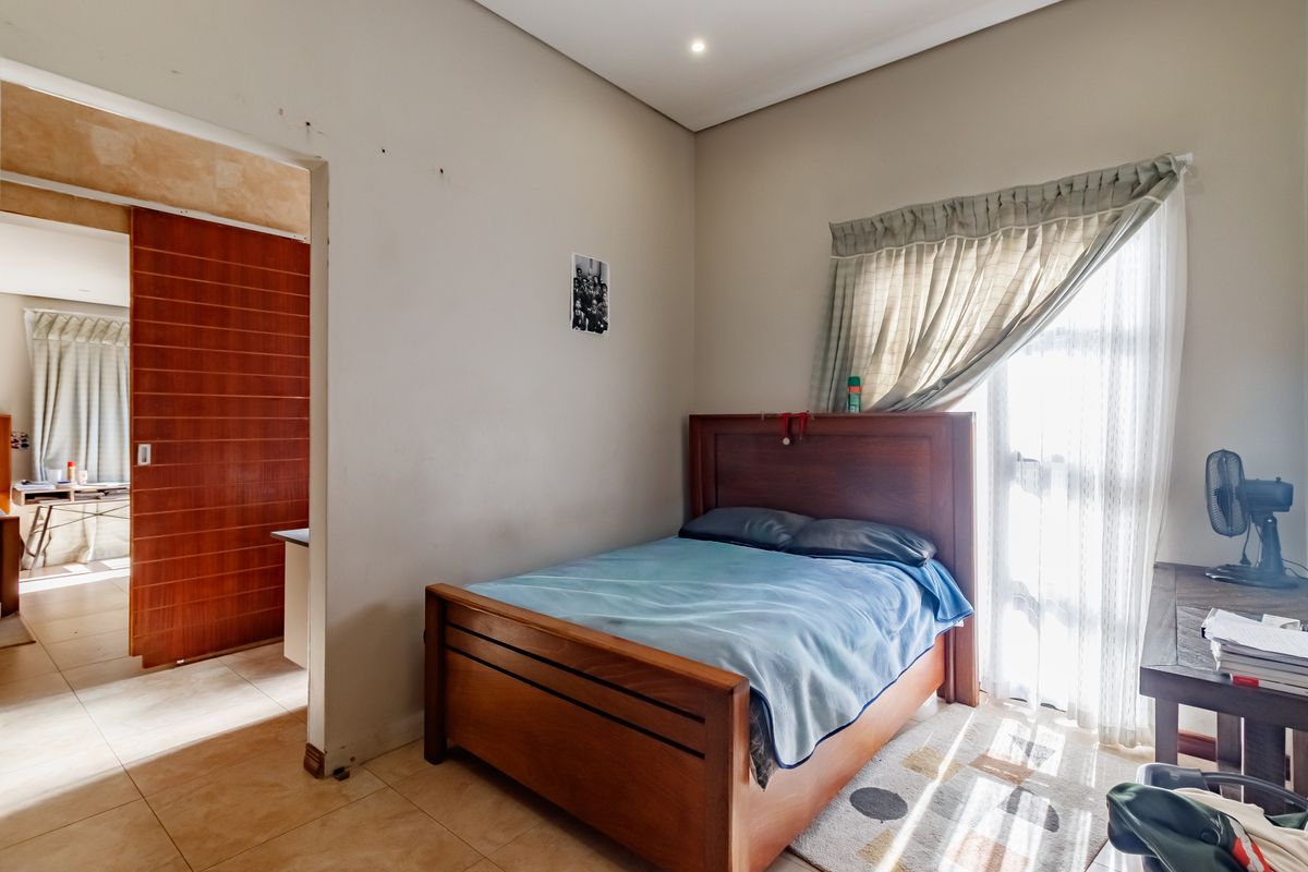 A bedroom featuring tiled flooring, recessed ceiling lighting, and a sliding door leading to an adjacent space.