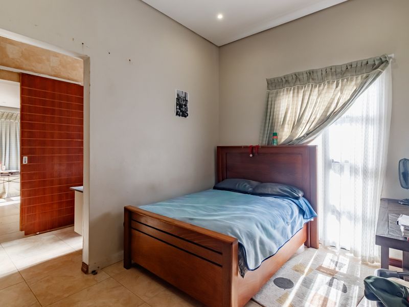 A bedroom featuring tiled flooring, recessed ceiling lighting, and a sliding door leading to an adjacent space.