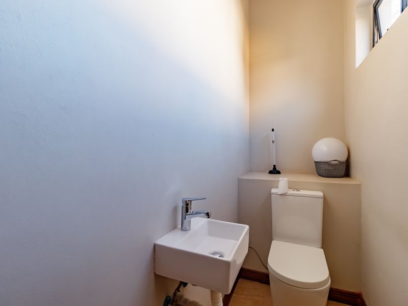 A compact guest bathroom featuring a modern wall-mounted basin, chrome mixer tap, and a standard close-coupled toilet.