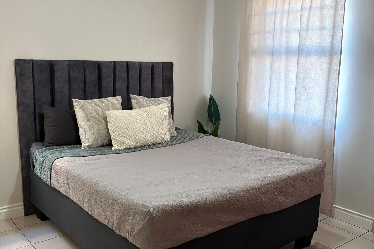 A well-maintained bedroom featuring neutral wall tones, tiled flooring, and classic crown molding, providing a clean and comfortable living space.