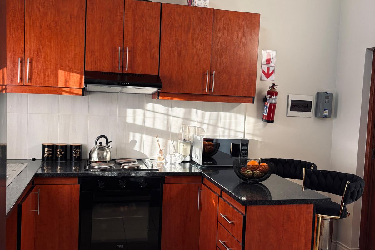 A functional kitchen featuring warm-toned wooden cabinetry, granite countertops, integrated appliances, and a tiled backsplash, offering a practical layout for daily cooking.