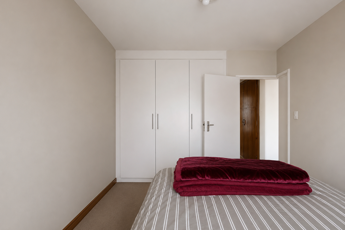 A clean bedroom featuring neutral walls, carpeted flooring, and ample built-in cupboard storage space.