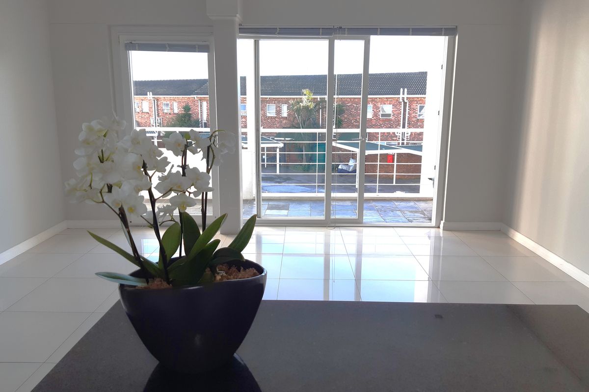 Bright and spacious living area featuring polished tiled floors and large sliding glass doors leading to an outdoor balcony.