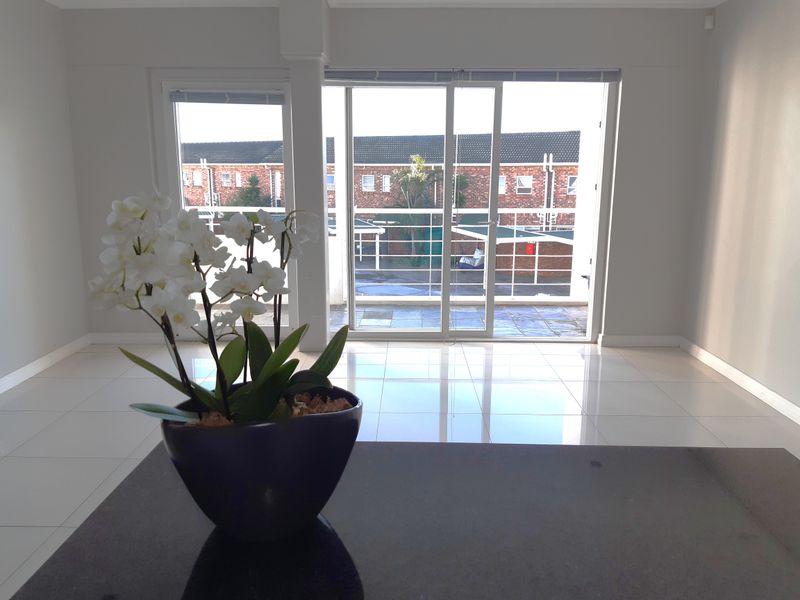 Bright and spacious living area featuring polished tiled floors and large sliding glass doors leading to an outdoor balcony.